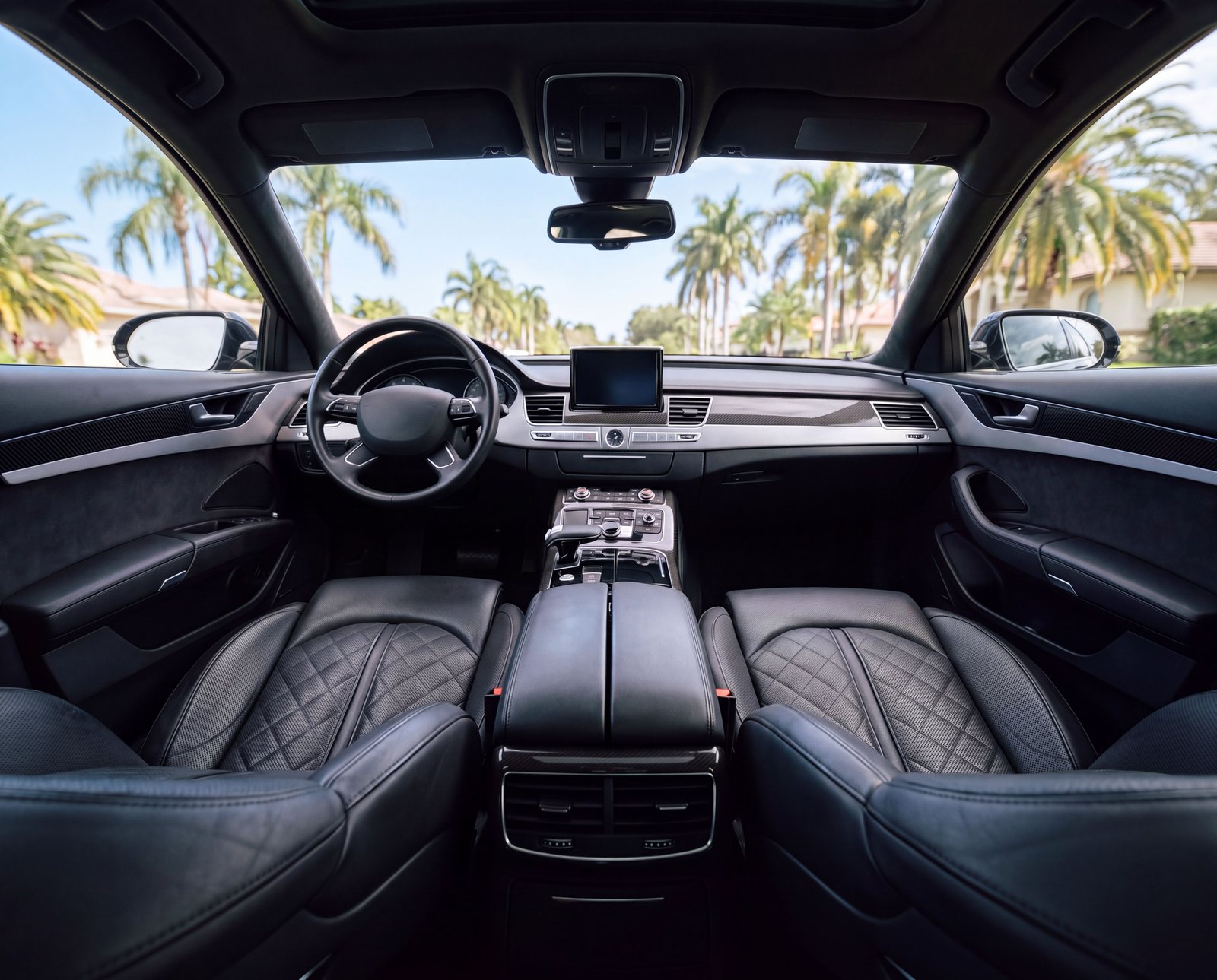 Detailed black quilted leather interior with palm trees seen through the windshield